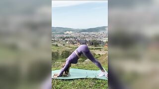 Doing yoga outdoors in a purple bodysuit